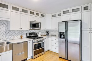 A modern kitchen with white cabinetry, stainless steel appliances, and a herringbone tile backsplash. - Fayetteville Fall Getaway | Family & Pet Friendly (Fayetteville)