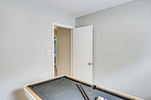 A room with a pool table, a door, and a light-colored wall. - Fayetteville Fall Getaway | Family & Pet Friendly (Fayetteville)