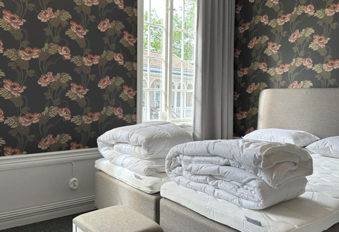 Une chambre à coucher avec un lit, deux tables de chevet et une fenêtre avec des rideaux.