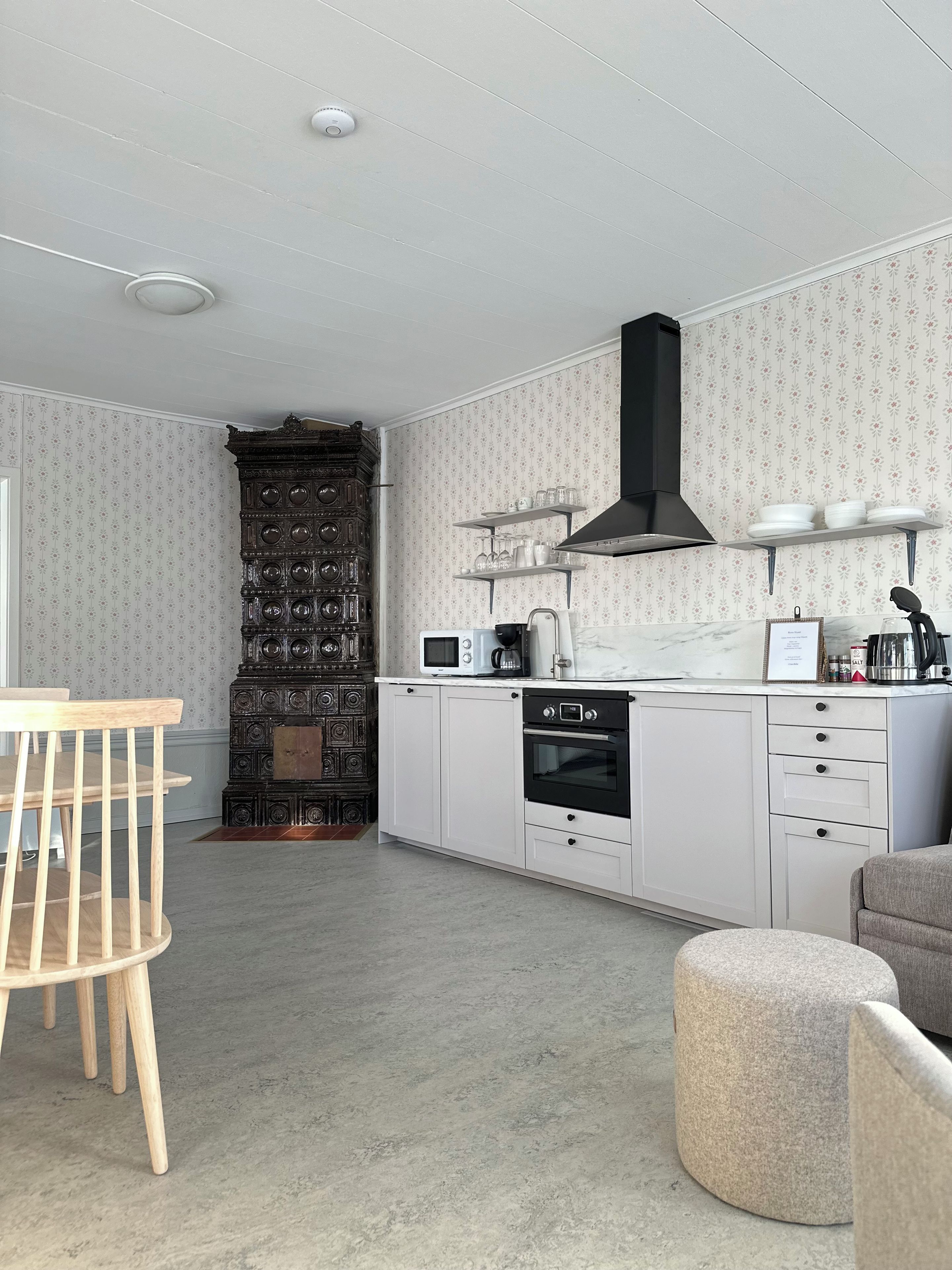 Une cuisine moderne avec des meubles blancs, une hotte noire et un four à micro-ondes.