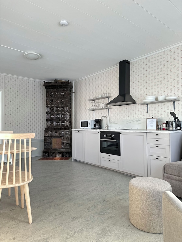 Una cocina moderna con armarios blancos, una campana extractora negra y un microondas.