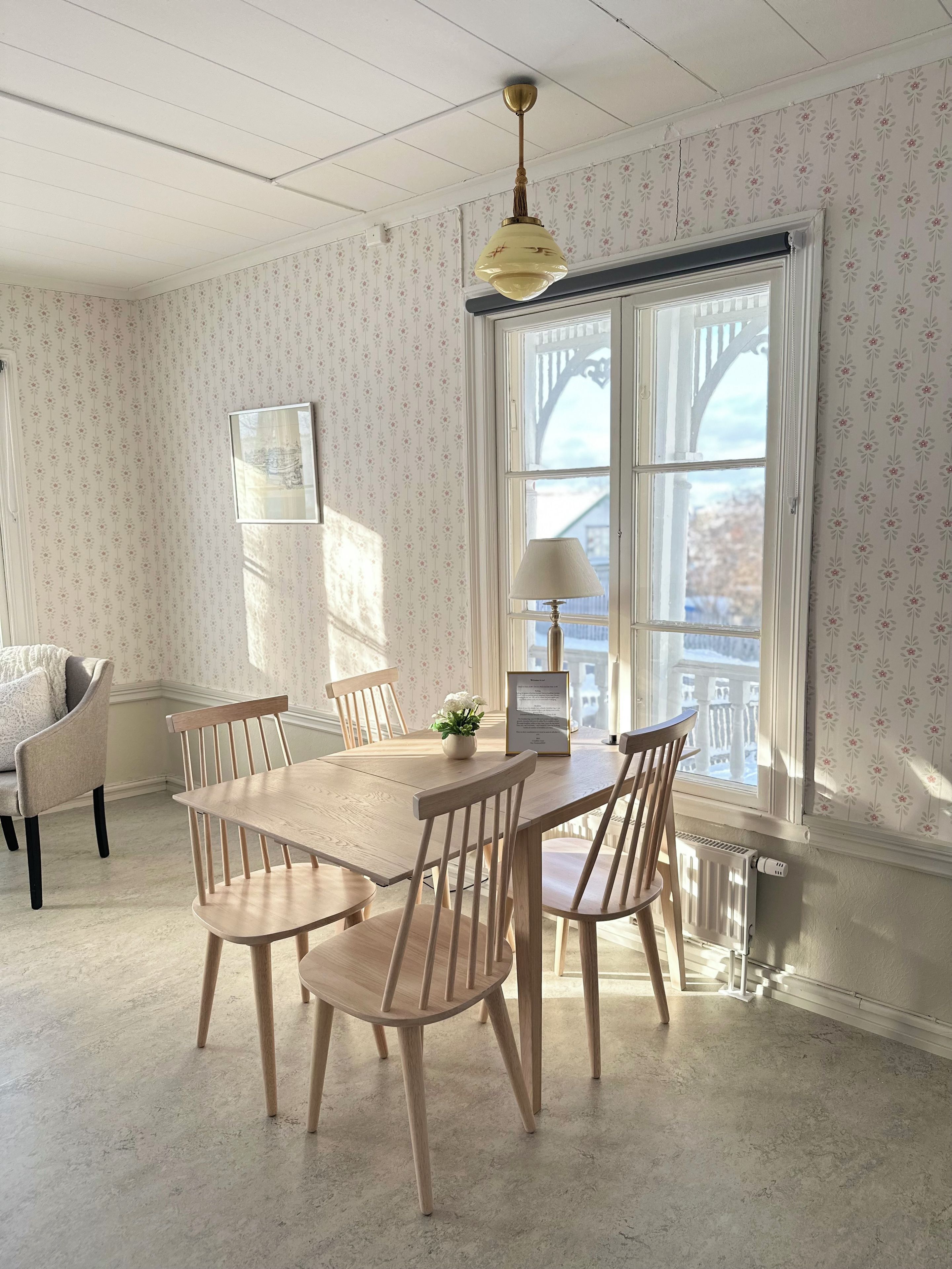 Un comedor con una mesa y sillas de madera, una lámpara colgante y una ventana con vistas.