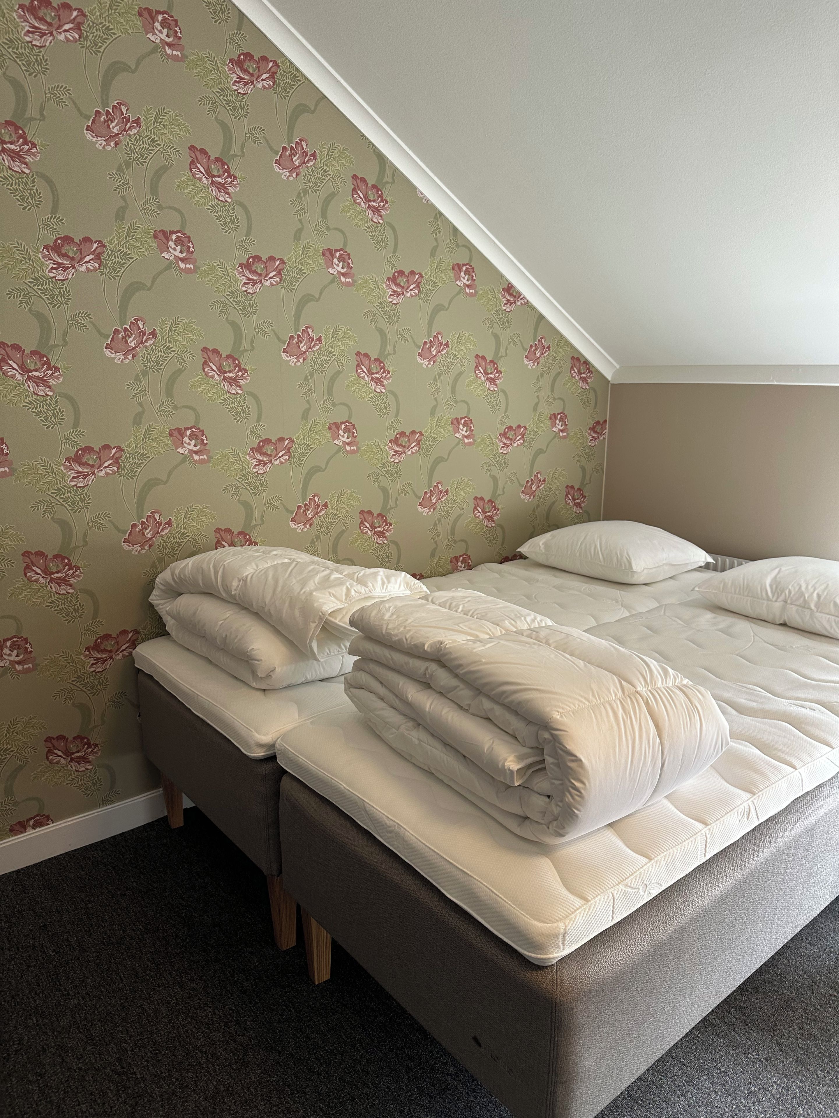 Une chambre à coucher avec un lit, des oreillers et un sol recouvert de moquette.