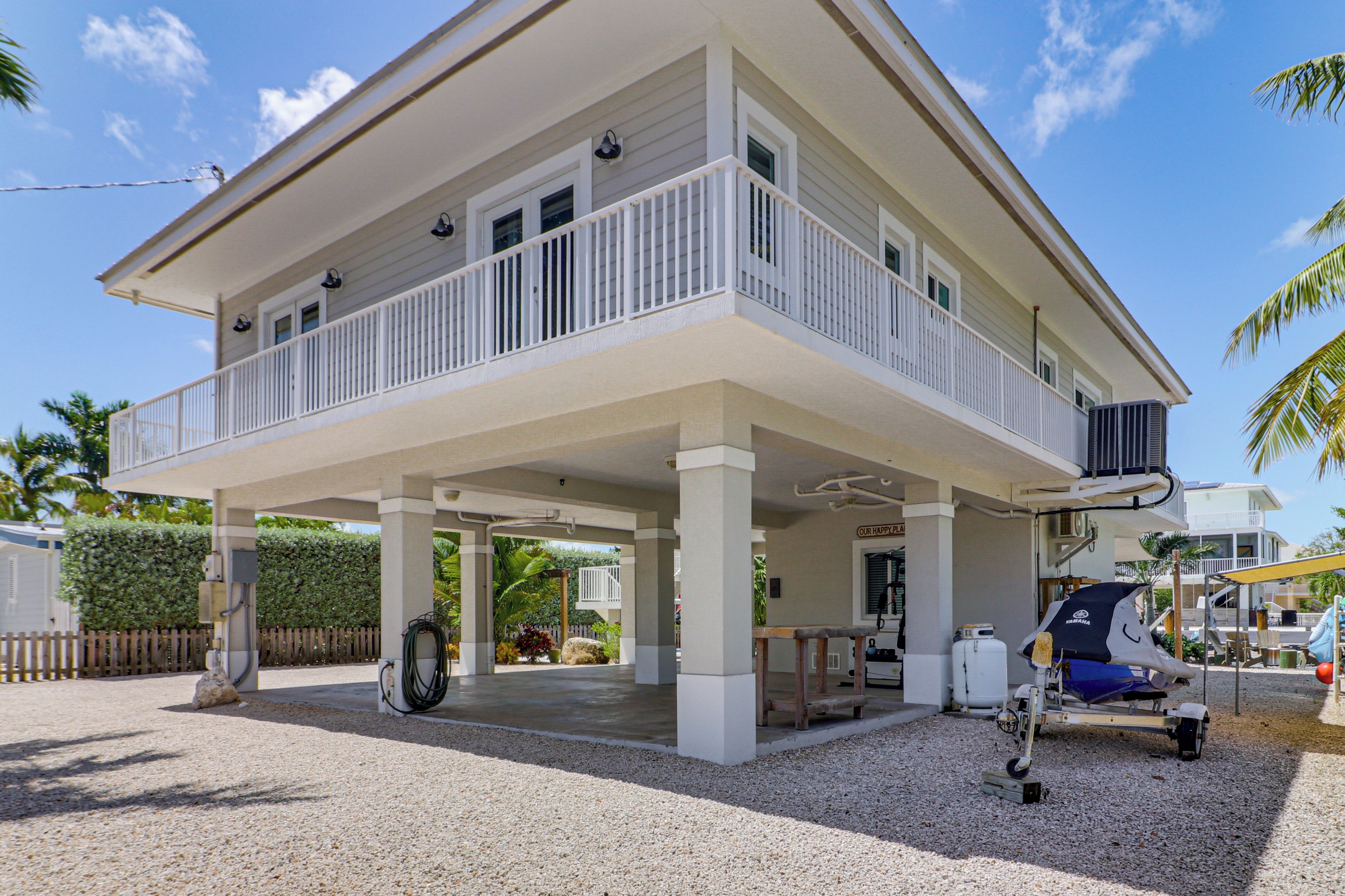 A two-story house with a covered porch, a small outdoor seating area, and a visible air conditioning unit.