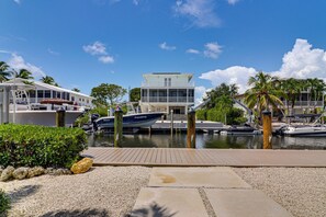 A marina with boats docked, a building with a balcony, and palm trees. - Private Dock & Pool: Waterfront Key Largo Home (Key Largo)