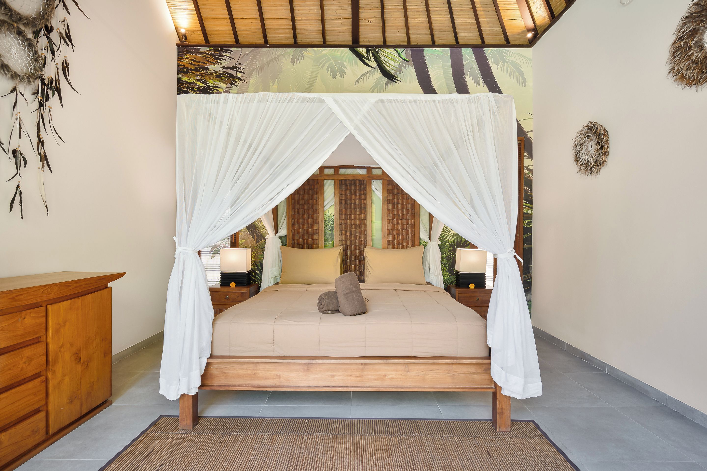 Un dormitorio con cama a dosel, cabecera de madera, lámparas de noche y un panel decorativo de fibra natural.
