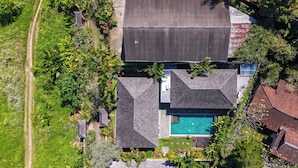 Vista aérea de uma propriedade residencial com piscina, vários telhados e vegetação exuberante.