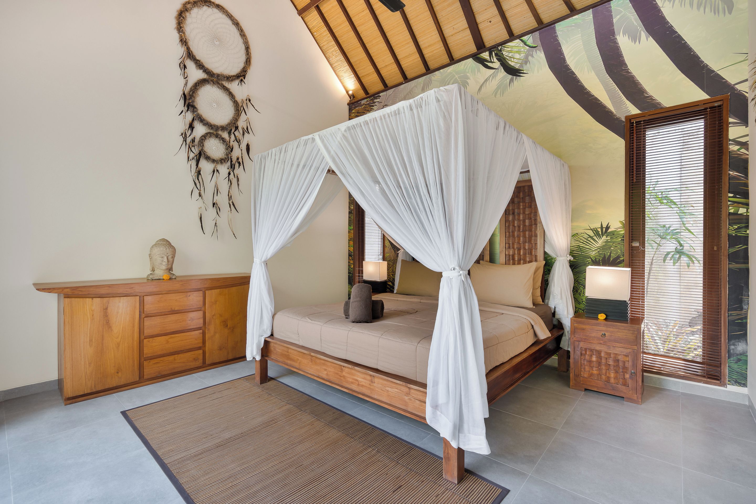 Un dormitorio con una cama con dosel, un armario de madera y un atrapasueños en la pared.