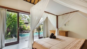 Quarto com cama de dossel, vista para uma piscina e um jardim tropical.