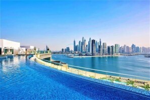 A waterfront hotel with a pool, a city skyline in the background, and a clear sky. - Neat Studio, Near the Monorail, Nakheel Mall and a Short Ride to Atlantis (Dubai)
