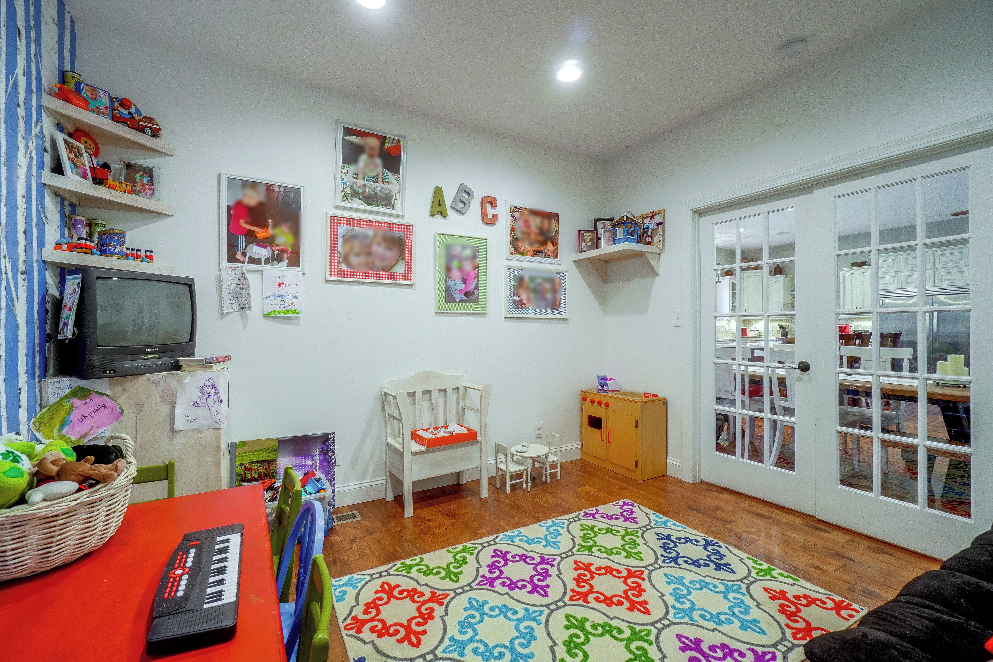 A child's playroom with a television, toys, and a colorful rug.