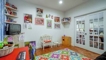 A child's playroom with a television, toys, and a colorful rug.
