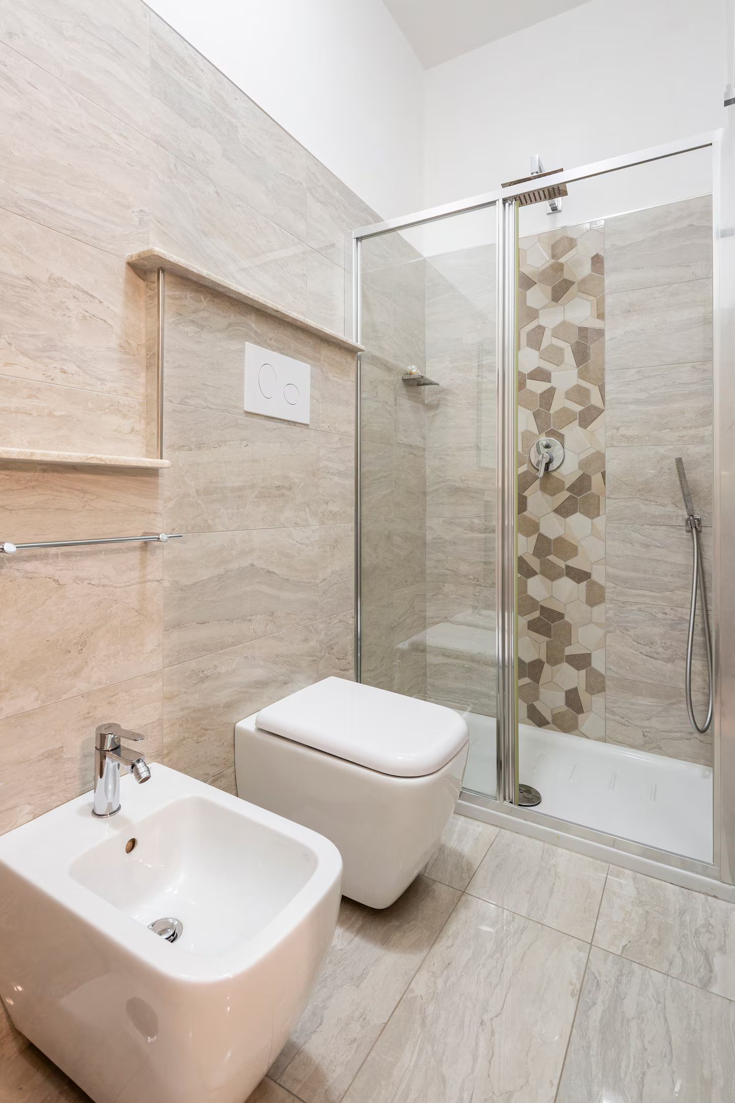 A modern bathroom with a glass-enclosed shower, a bidet, and a sink.