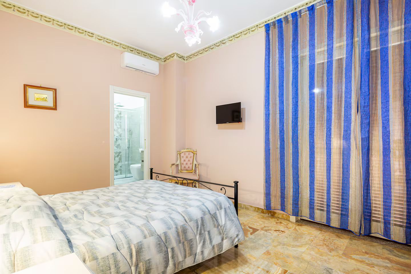 Une chambre à coucher comprenant un lit, une chaise, un téléviseur et un espace douche.