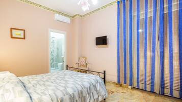 Une chambre à coucher comprenant un lit, une chaise, un téléviseur et un espace douche.