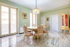 Une salle à manger avec un sol en marbre, un lustre et un buffet rouge.