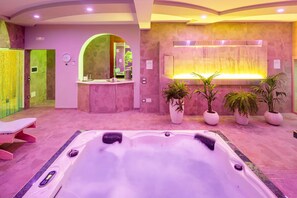 Une salle de spa dotée d’un grand jacuzzi, d’un comptoir d’accueil et de plusieurs plantes en pot.