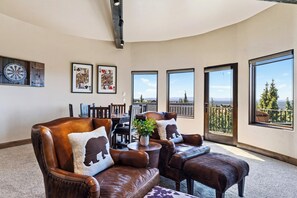 A spacious living room with leather furniture, a dartboard, and framed playing cards on the wall. - Spacious 6700 SQFT Home | 4 Ensuite Bedrms + Kids Bunkrm + Game Rm + Media Room (Powell Butte)