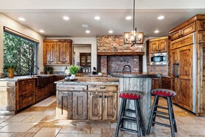 A spacious kitchen with a large island, wooden cabinets, and a stone backsplash. - Spacious 6700 SQFT Home | 4 Ensuite Bedrms + Kids Bunkrm + Game Rm + Media Room (Powell Butte)