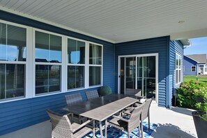 A covered patio with a table and chairs, large windows, and a sliding glass door. - Stylish Waterfront Home w/ Views in Lewes! (Lewes)