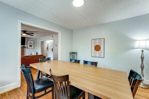 A dining area with a long wooden table, black chairs, and a lamp. - Commute to ATL! Home Near Canton St Eats (Roswell)