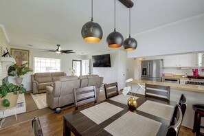 Una sala de estar moderna con sofá, mesa de comedor y zona de cocina con electrodomésticos.