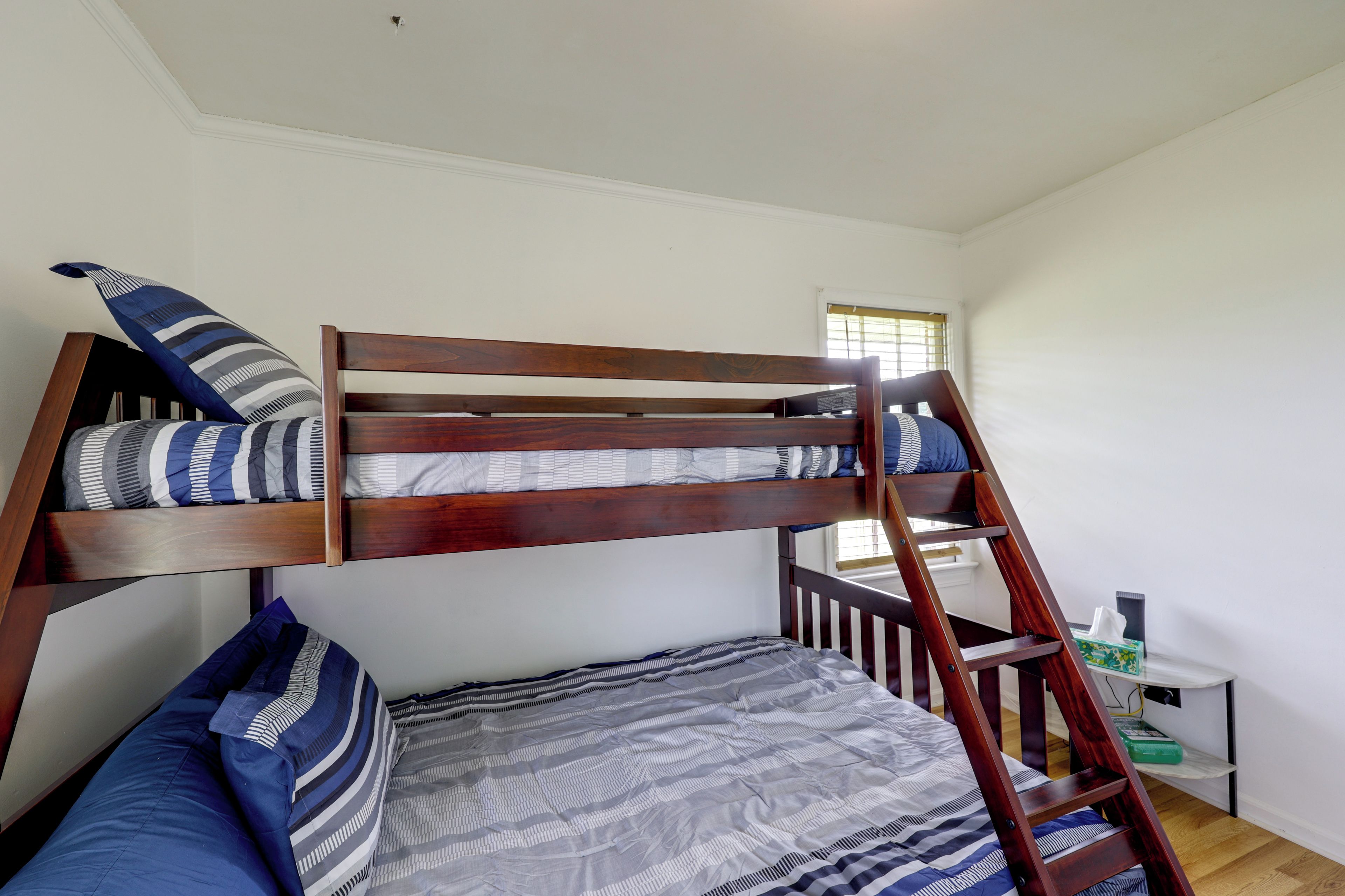 Uma cama box com escada, travesseiros e um cobertor.