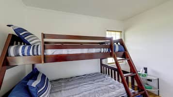 Uma cama box com escada, travesseiros e um cobertor.