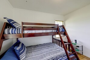 Una cama litera con escalera, almohadas y una manta.