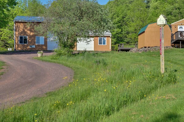 A rural property with a dirt road, wooden cabins, and a small shed.