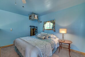 A bedroom with a bed, a nightstand, a window with curtains, and a ceiling fan.