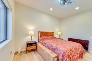 Ein Schlafzimmer mit einem hölzernen Bett, zwei Nachttischen mit Lampen, einem Fenster und einem Deckenventilator.
