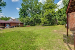 A backyard with a grassy lawn, a brick building, and trees.
