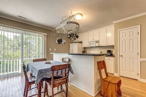 A kitchen with white cabinets, a microwave, and a hanging pot rack.