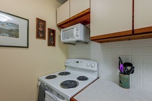 A kitchen with a stove, microwave, and a utensil holder.