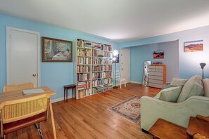 A living room with a bookshelf, a dining table, a sofa, and a rug.