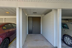 A narrow corridor with a closed door at the end, flanked by two parked cars.