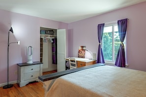 A bedroom with a bed, a desk, a wardrobe, and a window with curtains.