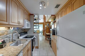 A kitchen with wooden cabinets, a stainless steel sink, a microwave, and a refrigerator. - Pool Access! 'The Palmetto House' in Clermont (Clermont)