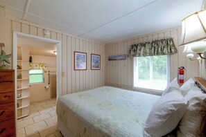 A bedroom with a bed, a window with blinds, a wall-mounted shelf, and a door leading to a bathroom. - Pool Access! 'The Palmetto House' in Clermont (Clermont)