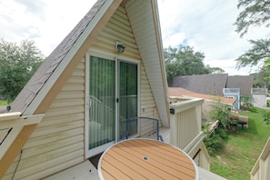 Il s’agit d’une propriété résidentielle dotée d’un toit en pente, d’une porte-fenêtre coulissante, d’une terrasse en bois et d’un petit espace extérieur aménagé pour s’asseoir.