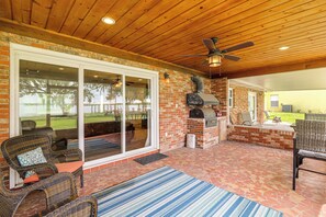 Eine Terrasse im Freien mit Kamin aus Backsteinen, Korbmöbeln und Deckenventilator.