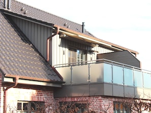 A residential building with a sloped roof, a balcony, and a brick facade. - Holiday Apartment 'Kleine Meerzeit Zingst' with Gas Fireplace, Underfloor Heating, Balcony, Wi-Fi, Central & Quiet (Zingst)