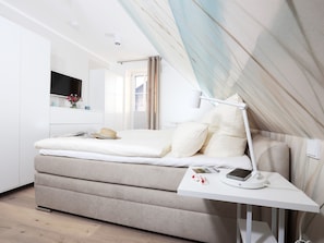Quarto moderno com cama, mesa de cabeceira e janela.