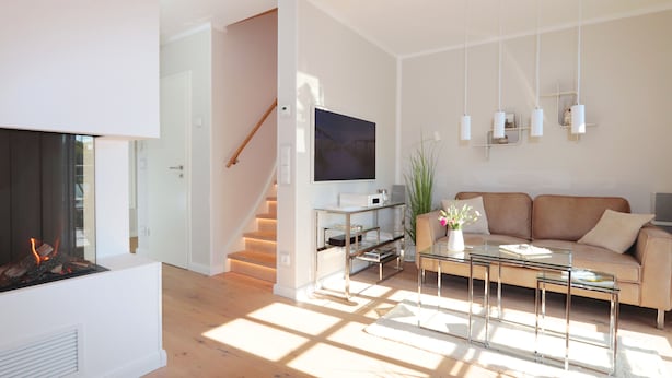 Ein modernes Wohnzimmer mit Kamin, einer Couch, einem Couchtisch und einer Treppe.
