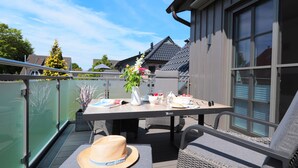Eine Außenpatio mit Esstisch, Korbmöbeln und einem dekorativen Hut auf dem Boden.