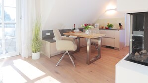 Eine moderne Küche mit Essbereich, einem Blumentopf und einem Glastisch.