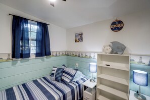 A room with a single bed, a desk, and a shelf with decorative items. - Walk to Lake Ontario! 'Minnow Cottage' (Kent)