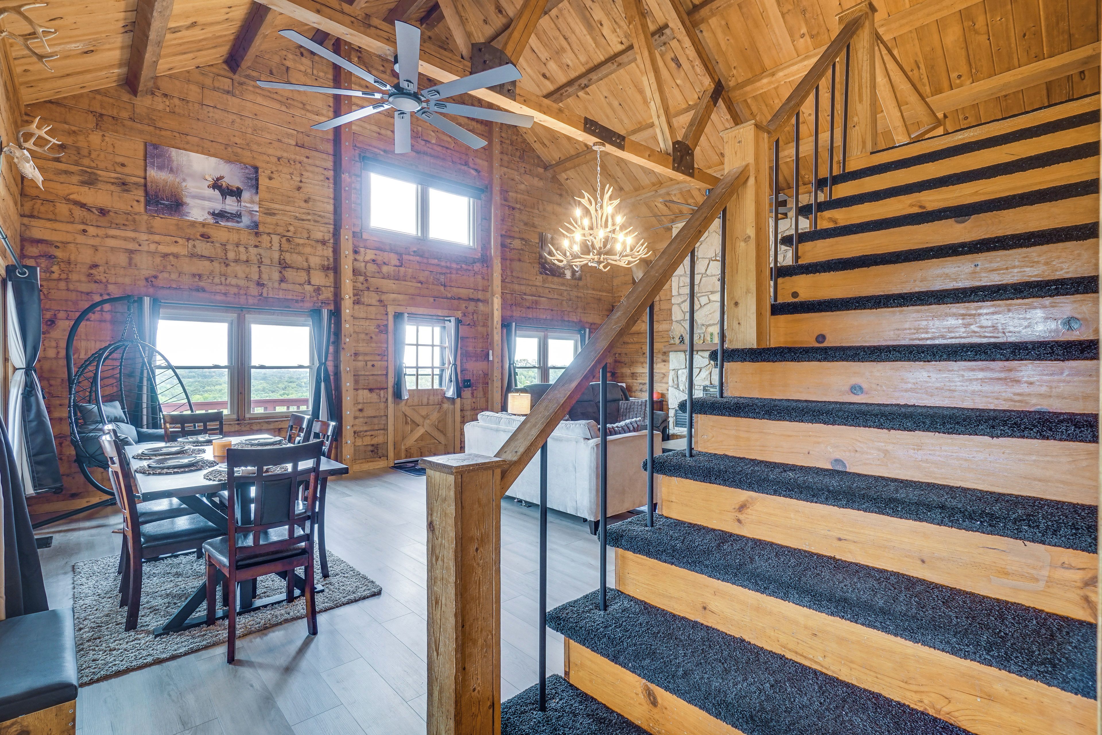 A rustic interior with a wooden staircase, a dining area, and a chandelier.