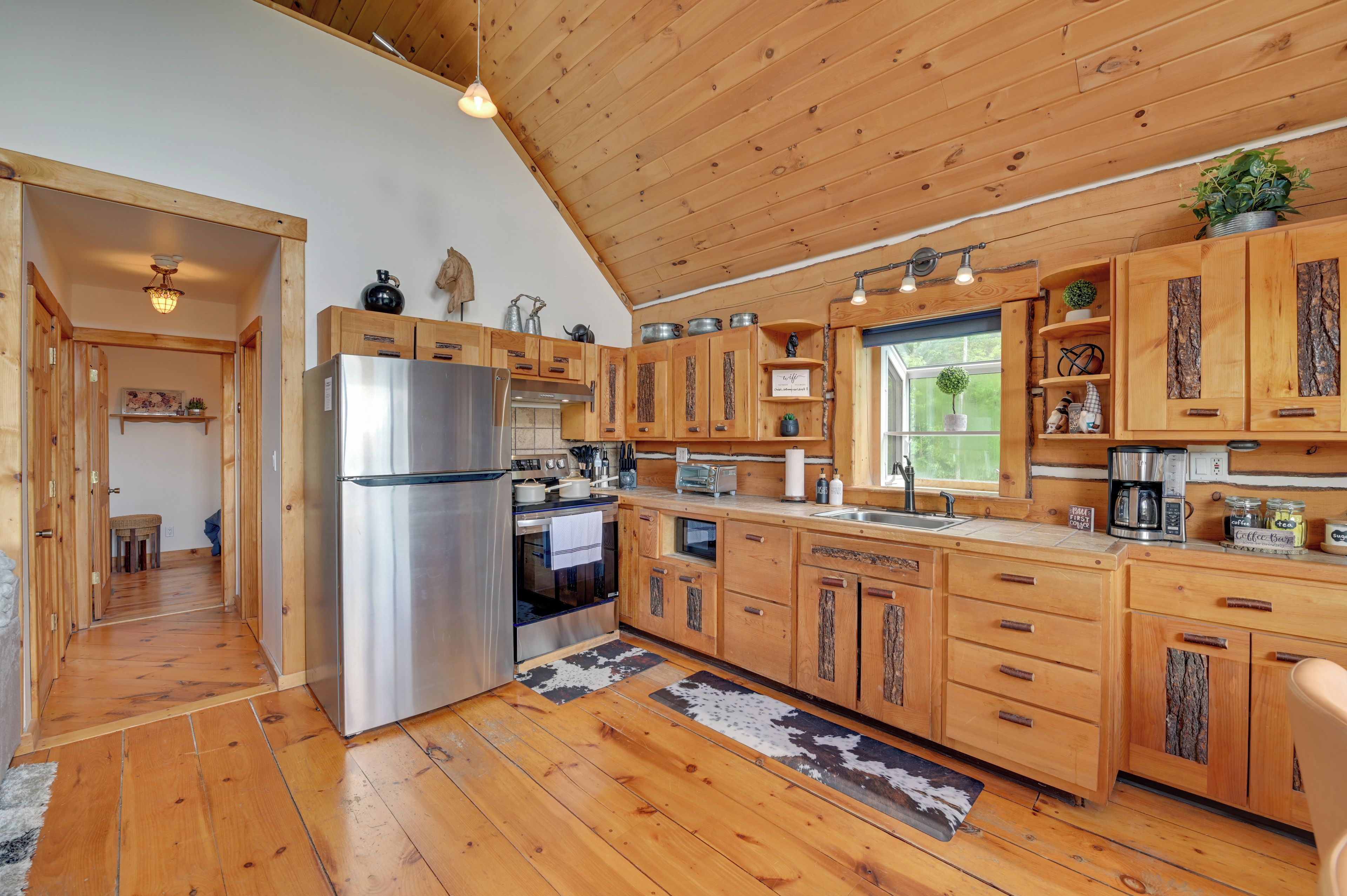 A wooden kitchen with a stainless steel refrigerator, wooden cabinets, and a window providing natural light.